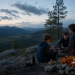 Father and children gathered around a small fire with mountains in the background